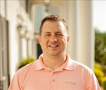 Man in pink shirt in front of white building 