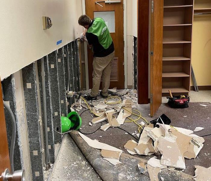 SERVPRO technician in a classroom with flood cuts on a wall